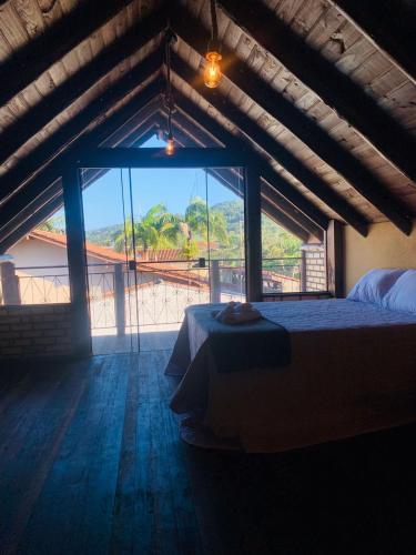 a bedroom with a bed and a large window at Encanto Chalés – 150m da Praia Grande – Penha – SC in Penha