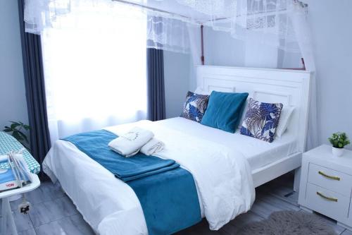 a bedroom with a white bed with blue pillows at Furnished 1BR Embakasi by LaMeg in Nairobi