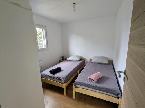 deux lits dans une petite pièce avec une fenêtre dans l'établissement Au Mouquet, à Parentis-en-Born