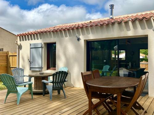 une terrasse en bois avec des chaises et une table. dans l'établissement Maison Charme Proche Plage et Forêt avec Jardin, WiFi, BBQ, et Pistes Cyclables à Proximité - FR-1-652-39, à Saint-Jean-de-Monts