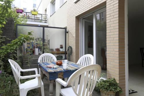 une table bleue avec quatre chaises blanches sur une terrasse dans l'établissement Private room with terrace in shared house, à Saint-Ouen