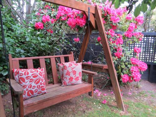 a wooden bench with two pillows and pink flowers at The Loft Bed and Breakfast in Taupo