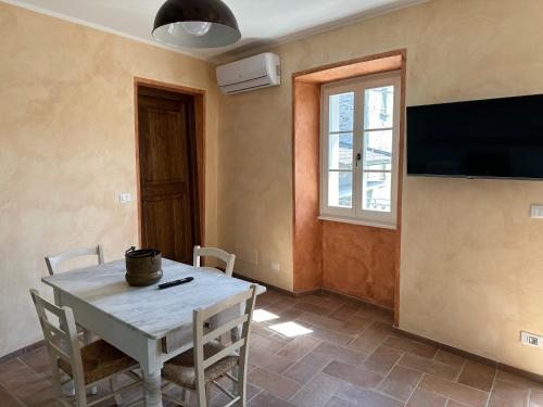 a dining room with a table and a tv on the wall at Nel Caruggio - B&B in Mornese