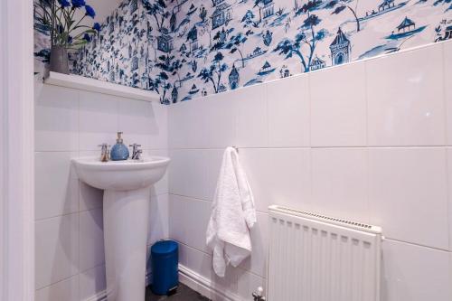 a bathroom with a sink and blue and white wallpaper at Luxury 3-bed house - Rothwell Gardens - 10mins from Leeds city centre in Rothwell