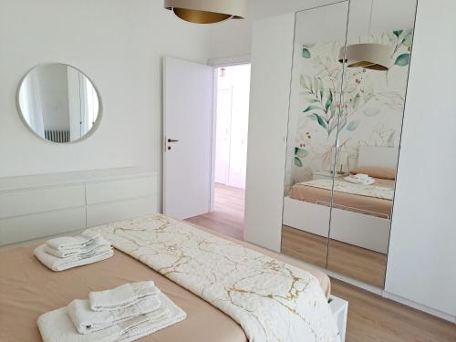 a white bedroom with a bed with a mirror at Golden Lake View in Lierna
