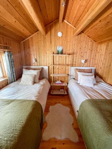 two beds in a room with wooden walls at Laplandliv cabin on the lake with hottub in Björkliden
