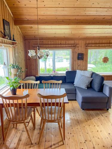 a living room with a blue couch and a table and chairs at Laplandliv cabin on the lake with hottub in Björkliden