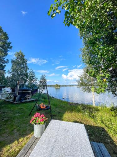 a picnic table next to a lake with a swing at Laplandliv cabin on the lake with hottub in Björkliden