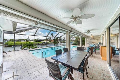 a patio with a table and chairs and a pool at Honolulu East - Vacation home with heated pool and Gulf-access canal in Cape Coral