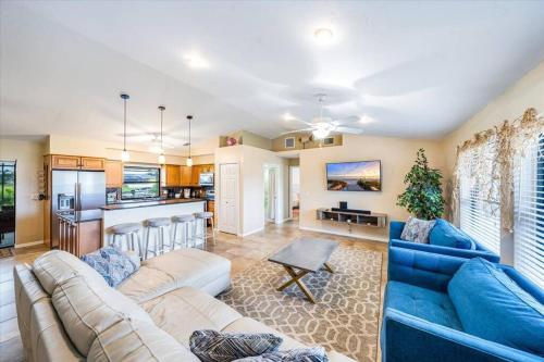 a living room with a blue couch and a kitchen at Honolulu East - Vacation home with heated pool and Gulf-access canal in Cape Coral