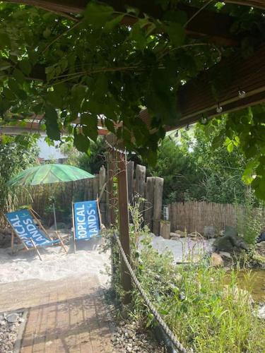 a chair and a green umbrella in a yard at Strandlust Döbeln - Bungalow für eine gemütliche Auszeit im Herbst in Döbeln