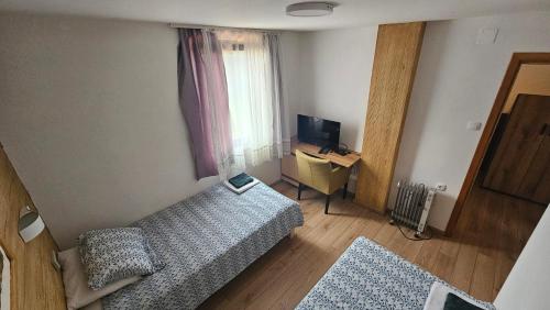 a small room with a bed and a desk with a laptop at Ruža vetrova in Kušići