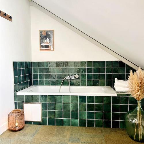a green tiled bathroom with a bath tub and a staircase at Enchanté in Jodoigne