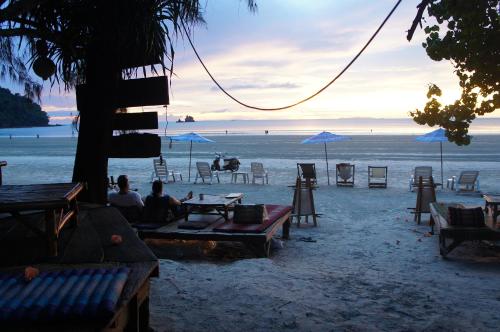 a group of people sitting at tables on a beach at Lazy Hut in Ko Phayam