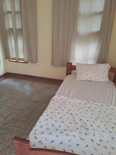 a bedroom with a bed with a pillow and windows at The Paradise In Kilimanjaro in Moshi