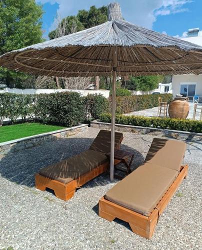two beds and an umbrella on a patio at Enigma Boutique Houses Koxyli in Marmarion