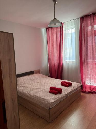 a bedroom with a bed with two red pillows on it at Апартамент Александър in Sunny Beach