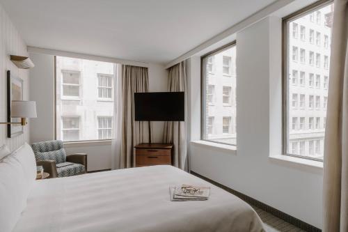 a hotel room with a bed and a tv and windows at Club Quarters Hotel Central Loop, Chicago in Chicago