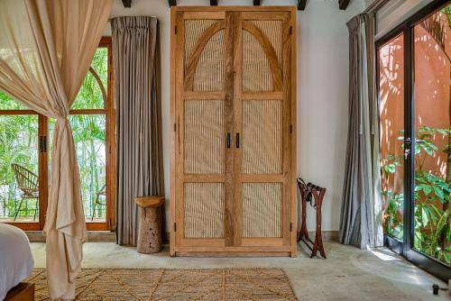 a bedroom with a wooden door and windows at Maxwell Residences at Indah in Puerto Vallarta