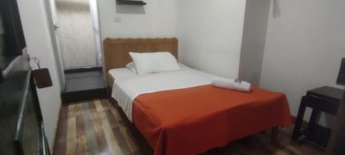 a small bedroom with a bed with an orange blanket at HOTEL LA GAITANA HEROINA INDIGENA in San Agustín