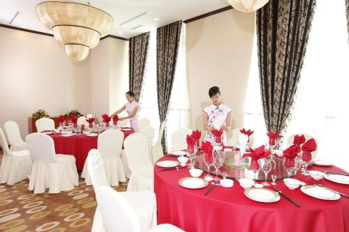 two people standing in front of a table with red and white tables at Majestic Mong Cai Hotel in Móng Cái