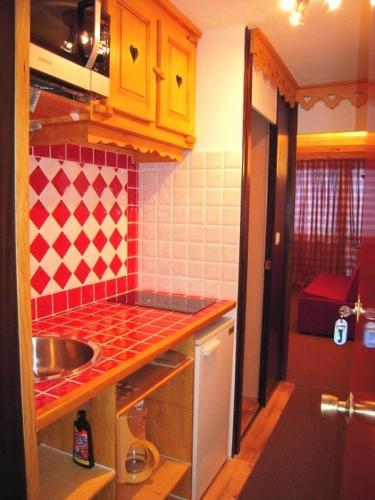Elle comprend une petite cuisine avec un évier et du carrelage rouge et blanc. dans l'établissement Résidence Le France - Studio 3/4 pers. 4 couchages LE FRANCE - PLAGNE CENTRE MAE-9114, à Aime La Plagne