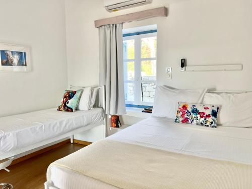 two beds in a room with white walls and a window at Little Troll House 1 in Chrissi Akti
