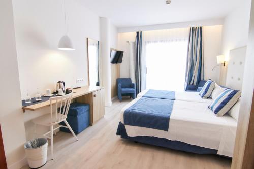 a hotel room with a bed and a desk and a window at Los Geranios in Port de Soller