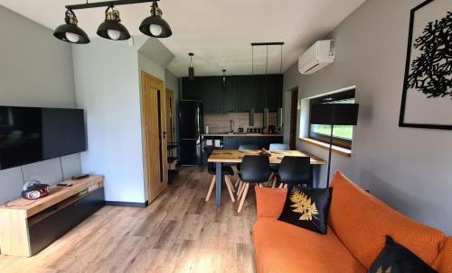 a living room with an orange couch and a table at Mazurskie Wzgórze Nad Jeziorem Isąg in Pelnik