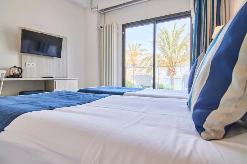 a bedroom with two beds and a large window at Los Geranios in Port de Soller
