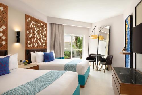 a hotel room with two beds and a desk at Secrets La Romana All-Inclusive Adult Only Resort & Spa in Bayahibe