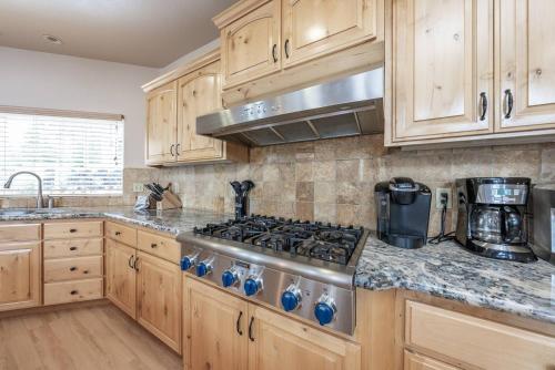 a kitchen with wooden cabinets and a stove top oven at Sunset Mountain Hot Tub, Fire Table, Epic Views in Shaver Lake