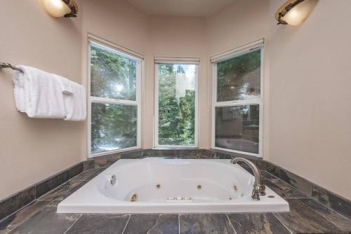 a white tub in a bathroom with windows at Sunset Mountain Hot Tub, Fire Table, Epic Views in Shaver Lake