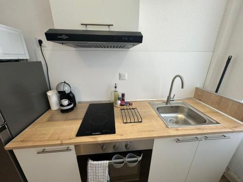 une petite cuisine avec un évier et une cuisinière dans l'établissement Studio cosy élégant et fonctionnel Centre ville, à Mulhouse