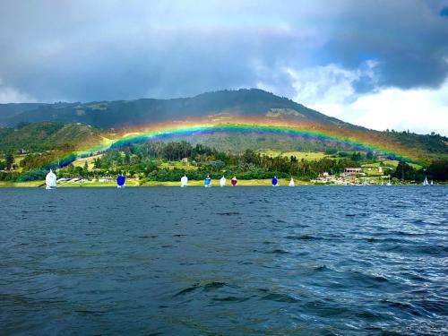 a rainbow over a body of water with people at Hotel El Dorado Guatavita in Guatavita