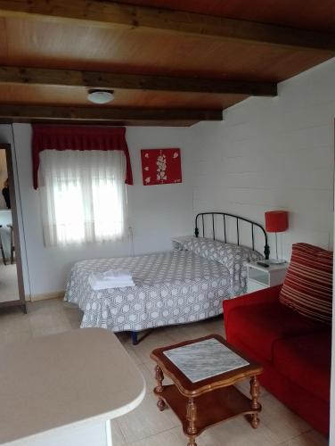 a bedroom with a bed and a red couch at Pensión Tabaza in Carreno
