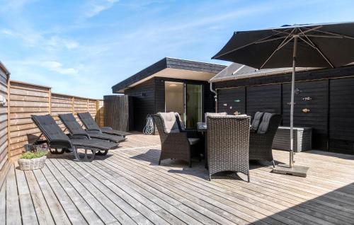 a deck with chairs and a table and an umbrella at Stunning Home In Fanø With Kitchen in Fanø