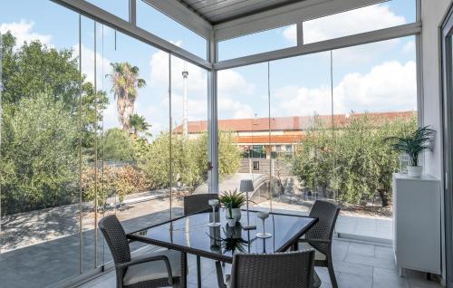 a dining room with a table and chairs and large windows at Stunning Home In Catenanuova in Centuripe