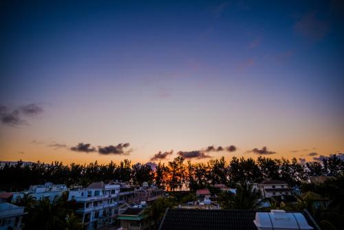 a sunset over a city with buildings and trees at L'Etoile Appartment in Flic-en-Flac