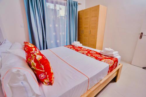 a bedroom with a bed with red and white pillows at L'Etoile Appartment in Flic-en-Flac