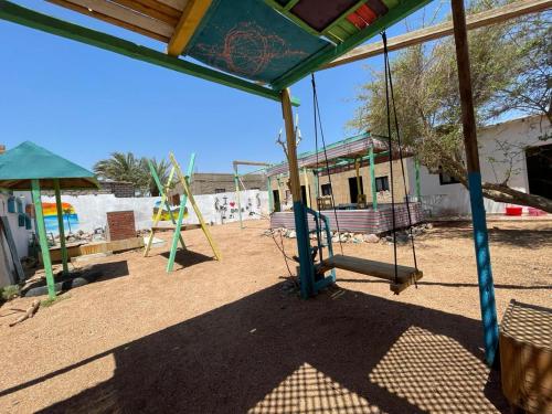 ein leerer Spielplatz mit Schaukeln und einer Rutsche in der Unterkunft Assala Camp in Dahab