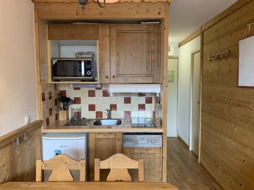 une petite cuisine avec un évier et un micro-ondes dans l'établissement Charmant studio cabine aux Ménuires, pied des pistes, balcon, animaux permis, accès télébenne gratuit - FR-1-452-43, aux Menuires