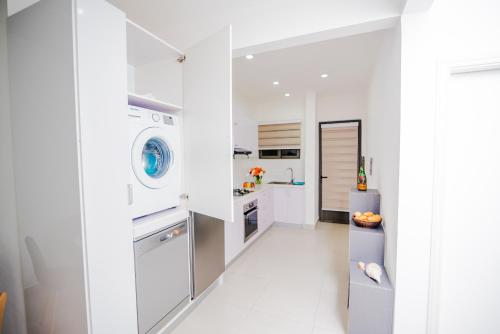 a white kitchen with a washer and dryer at L'Etoile Appartment in Flic-en-Flac
