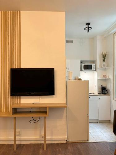 un salon avec une télévision à écran plat sur une table dans l'établissement Cozy Studio, à Paris