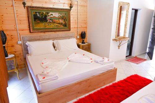 a bedroom with a large white bed with a red rug at Bujtina Syni Zi "Keshtjella" - Shengjin in Shëngjin