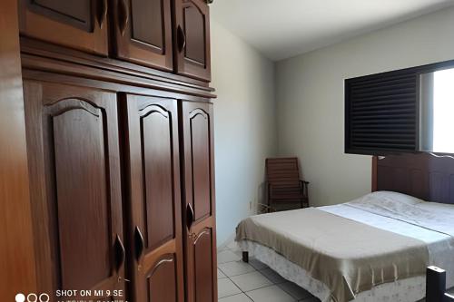 a bedroom with a bed and a large wooden cabinet at AP 04 DO CANTINHO DO SOSSEGO in Dourados
