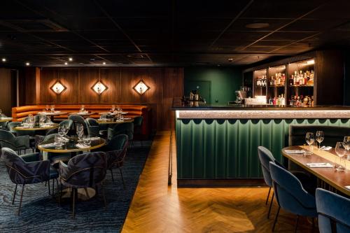 a restaurant with tables and chairs and a green bar at Club Quarters Hotel London City, London in London