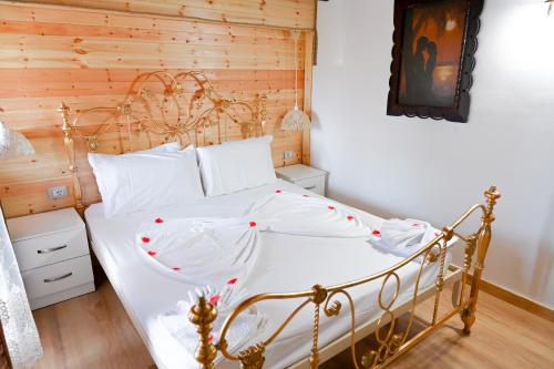 a bedroom with a white bed with a wooden wall at Bujtina Syni Zi "Keshtjella" - Shengjin in Shëngjin