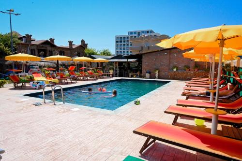 a pool with chairs and umbrellas and people in it at Bujtina Syni Zi "Keshtjella" - Shengjin in Shëngjin
