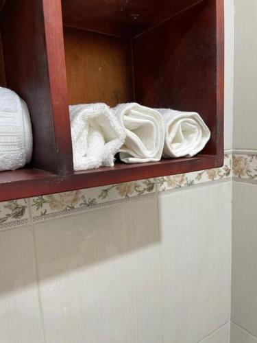 a wooden shelf with white towels on a wall at Blissful Homes in Kampala